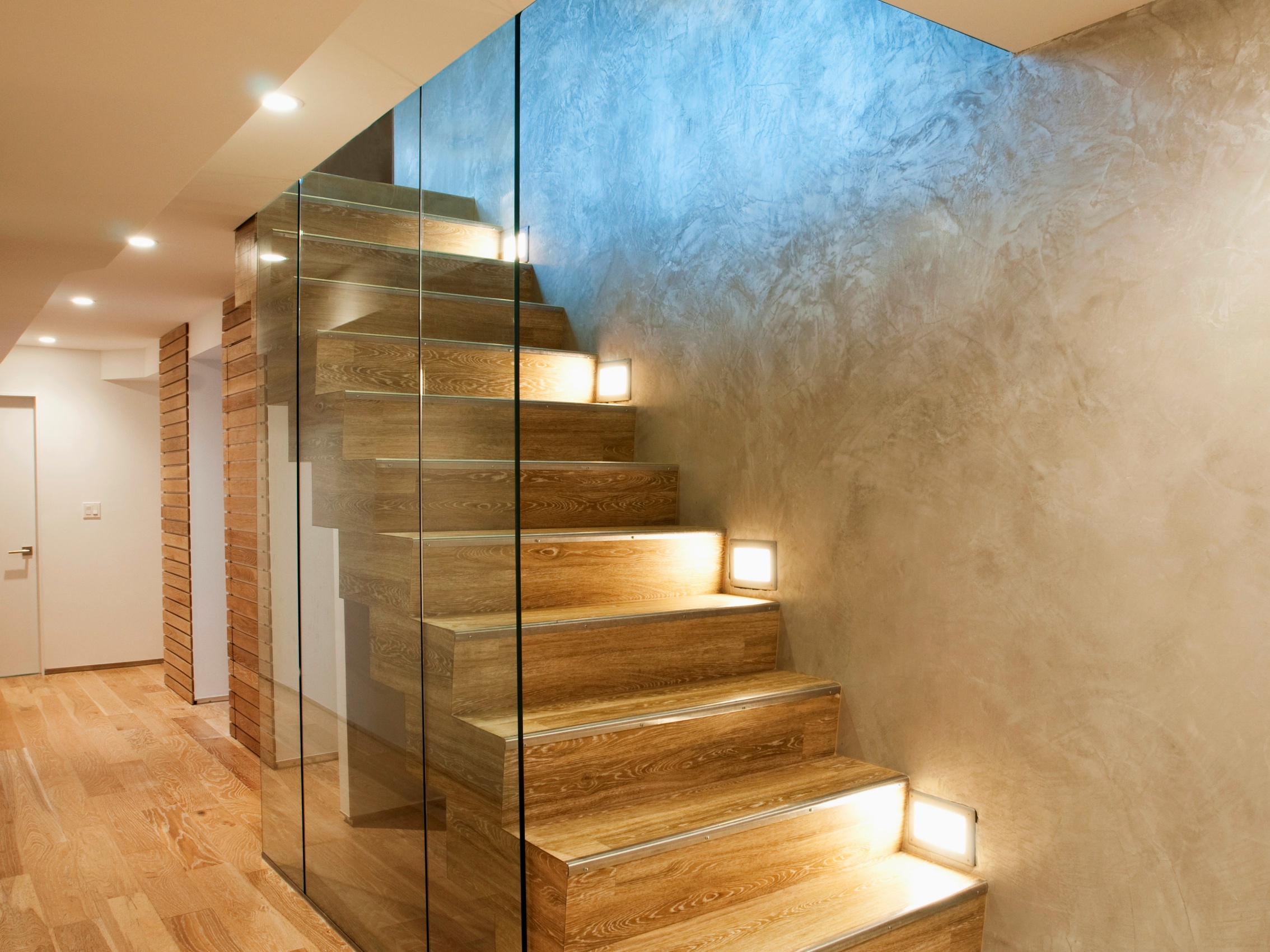 Warum entscheiden sich immer mehr Menschen für den Einsatz von LED-Streifen auf ihren Treppen?-Beleuchtung Case Sharing--Glastrennscheibe vor moderner Treppe mit Einbauleuchten in Wand eines minimalistischen Treppenhauses